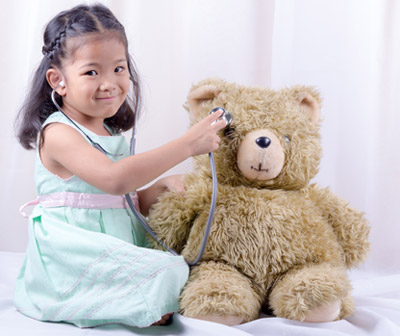 Young girl play-doctoring a teddy bear